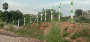 Green and white post fencing on sloped land, Chennai