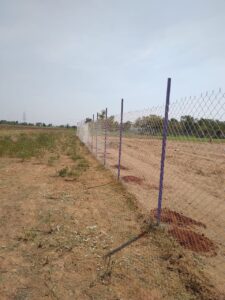 Chain link fence along open farmland in Chennai