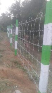 Barbed wire fence with green and white poles, Chennai